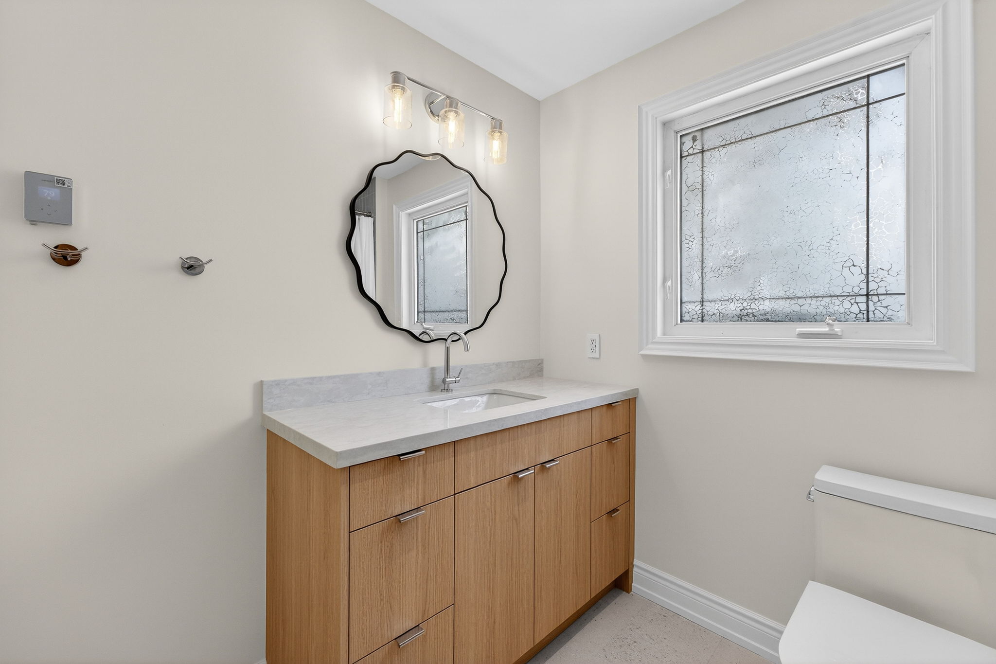 Natural oak vanity with quartz countertop and wavy black mirror Mississauga bathroom