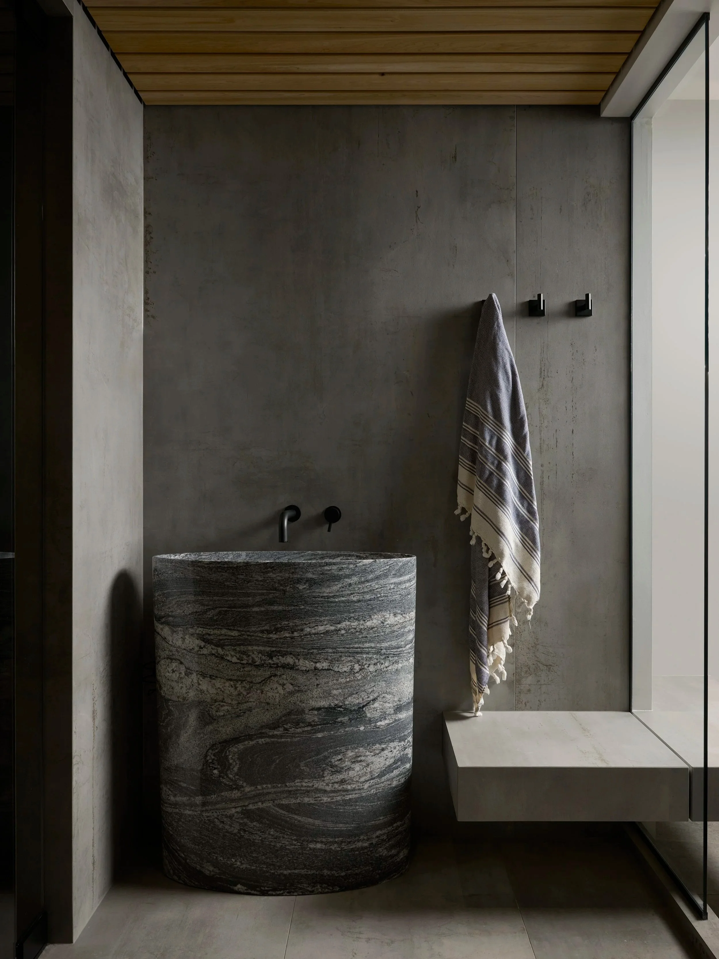 Carved stone vessel sink with microcement walls and cedar ceiling Toronto wellness suite